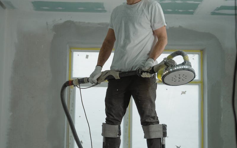 A construction worker using stilts for ceiling renovation indoors, enhancing space with expertise.