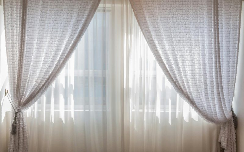 Sun shining through elegant white curtains in a cozy, modern interior setting.